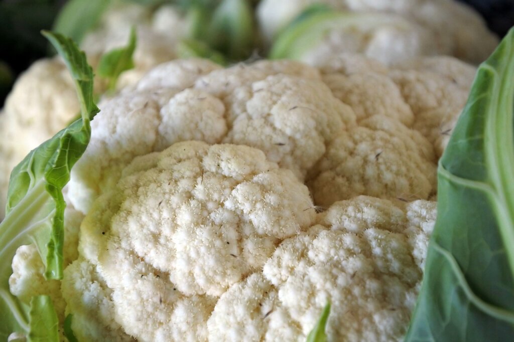 Nahaufnahme von frischem Blumenkohl mit teilweise grünen Blättern.