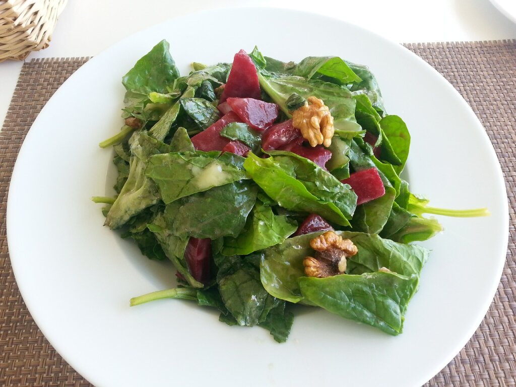 Ein Teller mit grünem Blattsalat, roten Rote-Bete-Stücken und Walnüssen.